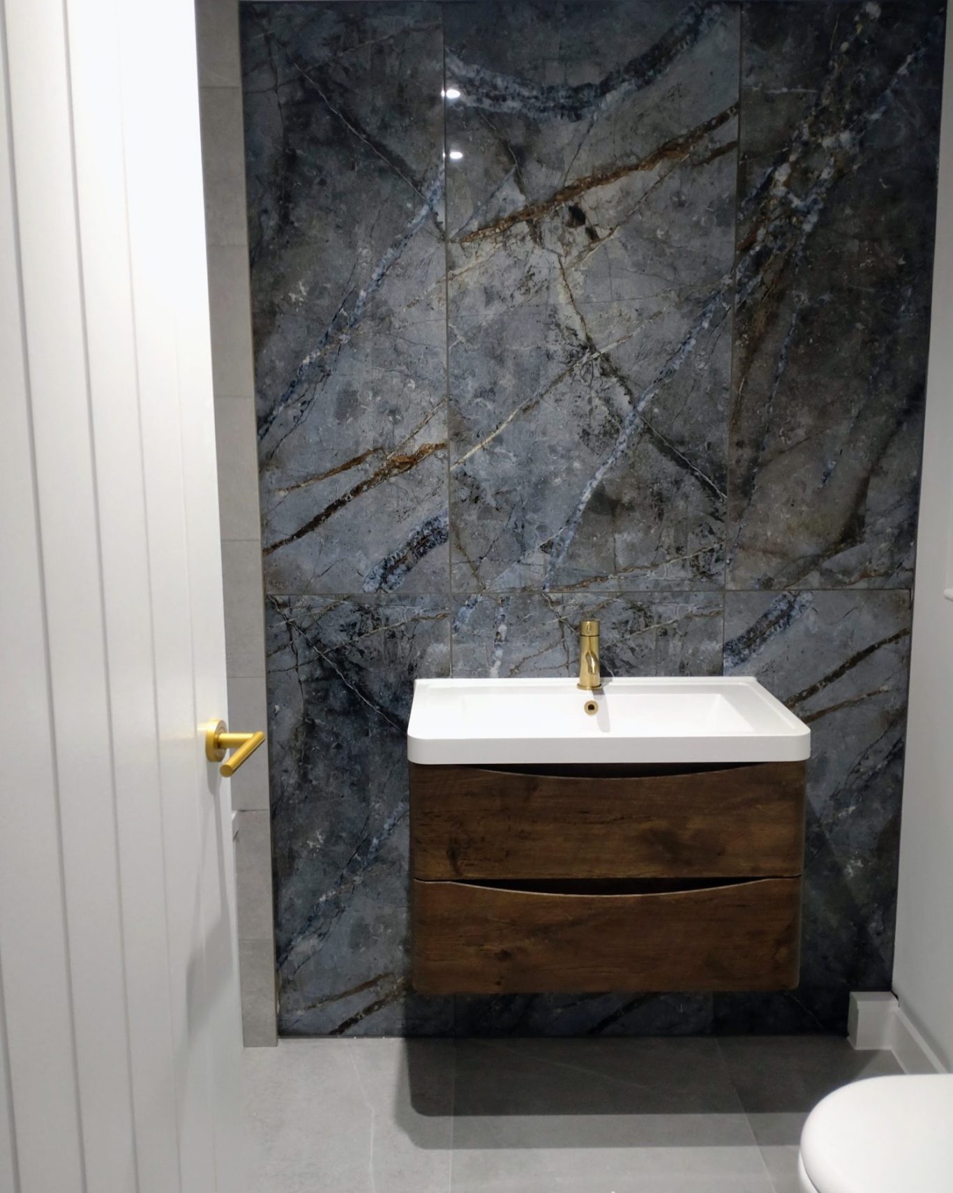 High end bathroom renovation featuring a floating vanity unit and dark marble tile.